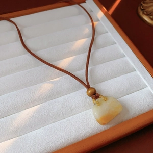 Close-up of retro necklace with yellow resin pendant and wooden bead on white tray