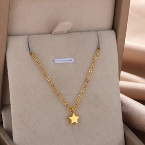 Detailed macro view of a gold-plated star pendant necklace on a soft beige jewelry display
