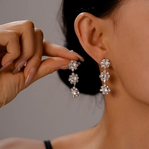 Close-up of silver tassel earrings with crystal flower charms and elegant diamond fringe