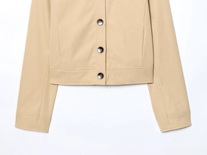 Detailed view of beige jacket hem with premium dark buttons and smooth fabric texture