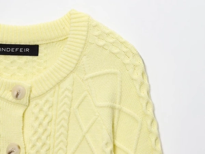 Close-up of cable knit texture and matte buttons on a lemon yellow women's cardigan