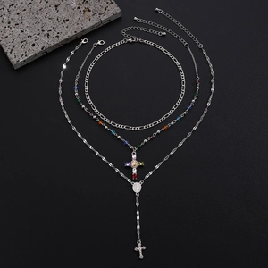 Macro detail of silver layered cross pendant necklace with colorful stones and rosary beads