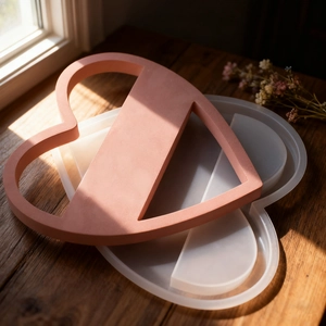 Detailed view of hollow heart-shaped resin mold and plaster ornament on dark wood base