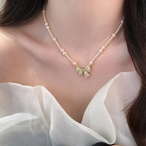 Detail van een vintage parelketting met een glanzende strikhanger van zirkonia-stenen.