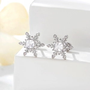 Elegant silver snowflake stud earrings with sparkling cubic zirconia on a white pedestal