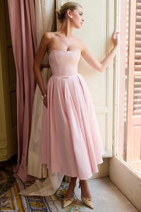 Detail of light pink strapless midi dress featuring pleated skirt and waist bow decoration