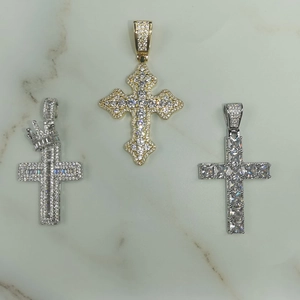 Détails des pendentifs croix en or et argent avec zircons sur marbre blanc