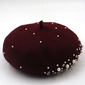 Detail showing elegant pearl and rhinestone accents on burgundy wool knit beret texture