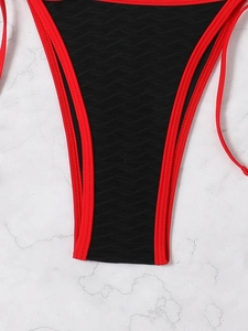 Detailed macro view of black bikini bottom with red trim and wave texture fabric