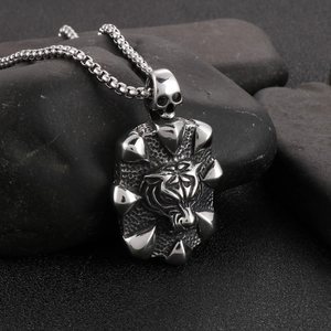 Macro shot of silver stainless steel tiger head and skull pendant on black stones
