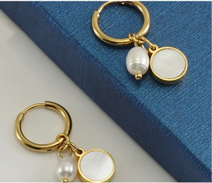 Detailed macro view of 18K gold-plated hoop earrings with pearl and shell pendants
