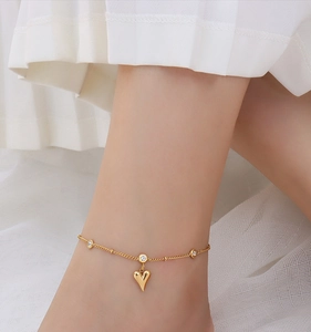 Detail of 18k gold plated titanium heart anklet with cubic zirconia on model's ankle