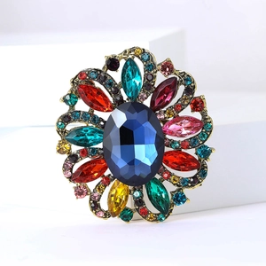 Close-up of vintage flower brooch with large blue gem and multicolored rhinestones