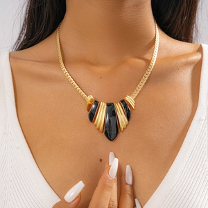 Close-up of a vintage-style gold plated chunky necklace with black enamel fan pendant