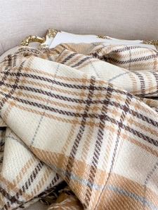 Close-up of soft plaid cashmere-feel scarf with beige check pattern and fringe details