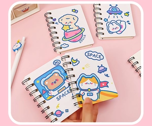 Detailed view of various mini cartoon astronaut spiral notebooks on pink background