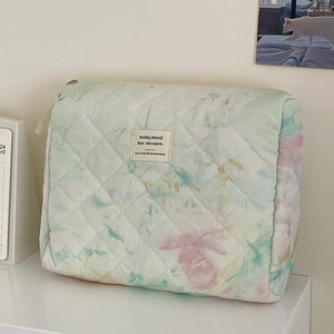Detailed macro view of quilted watercolor makeup bag with soft pastel tie-dye pattern