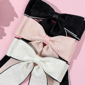Elegant ribbon bow hair clips in black, pink, and off-white fabric with jacquard texture
