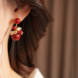 Dettaglio orecchini a fiore placcati oro 18K con perline rosse e zirconi indossati da modella