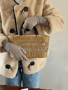 Detalle de bolso tote de paja trenzada con asas de cuero negro y forro de tela crema