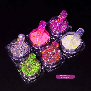 Macro shot of six vibrant reflective nail art glitter powders shown under flash light