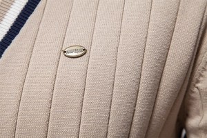 Dettaglio della maglia a coste kaki con placca in metallo del logo sulla giacca cardigan