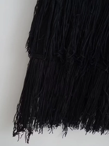 Gros plan détaillé montrant les couches de franges noires sur une robe en maille ajustée