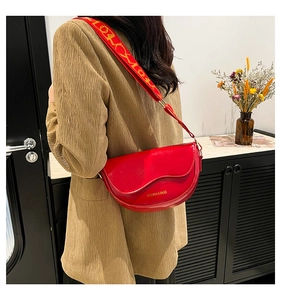 Detail of red saddle bag with wide shoulder strap featuring fashionable letter patterns