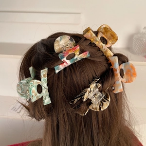 Detail of diverse acetate hair claws featuring marble patterns on a model hairstyle