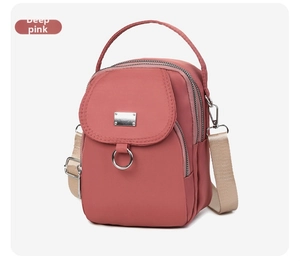Detail of dark pink nylon crossbody bag with silver zippers and adjustable woven strap