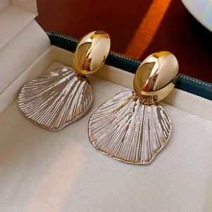 Macro view of gold and silver shell earrings in a premium dark green jewelry box
