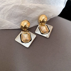 Gros plan de boucles d'oreilles géométriques avec sphères dorées et cristal serti