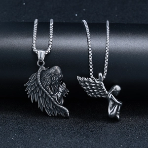 Gros plan de deux pendentifs anges en argent vieilli avec détails d'ailes sur socles
