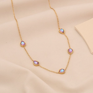 Dettaglio della collana d'oro con cinque pietre preziose viola a goccia su tessuto