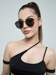 Close-up of stylish rectangle sunglasses with gold metal frame and black lenses on a model