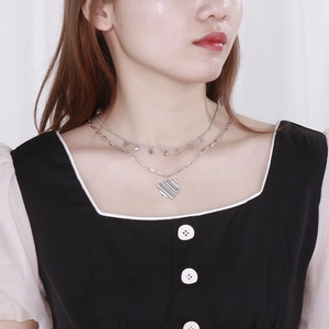 Gros plan d'un collier double épaisseur en acier inoxydable argenté avec pendentifs