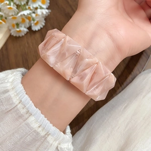 Detail of marble pattern acrylic geometric stretch bracelet worn on wrist for retro style