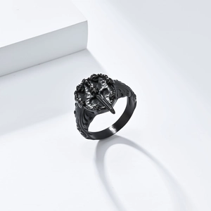 Detailed close-up of a black punk skull ring with intricate wing engravings and embossed textures
