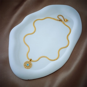 Golden snake chain necklace with blue evil eye round pendant on satin fabric