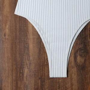 Detailed close-up of white ribbed texture swimwear fabric on dark wooden background