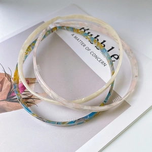 Close-up of three acetate headbands in beige, blue, and pink patterns on a magazine
