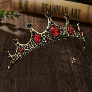 Detailed shot of a vintage gold crown with red and black gems on a dark wooden art background