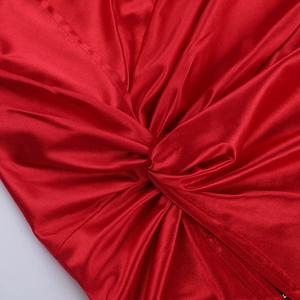 Close-up of red satin dress featuring elegant knot detail and glossy fabric texture
