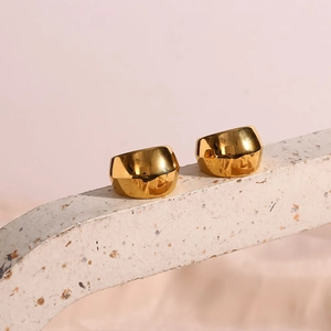 Gros plan de boucles d'oreilles créoles dorées 18K irrégulières sur base pierre