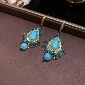 Detail of teardrop turquoise earrings with diamond accents and boho tassel fringe