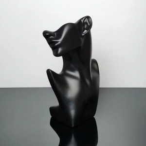 Detail view of a matte black jewelry display bust featuring profile silhouette and reflection