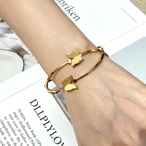 Macro view of gold-plated butterfly bangle with textured wings on a double-layer band