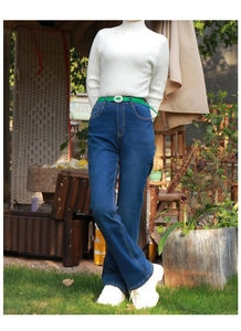 Detail of a thin green belt with pearl buckle paired with dark blue high waist jeans