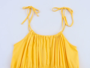 Detail of yellow linen-style dress with adjustable tie straps and pleated neckline