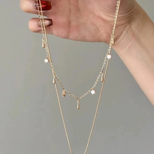 Detail of double-layer gold necklace featuring clear crystals and teardrop pendants